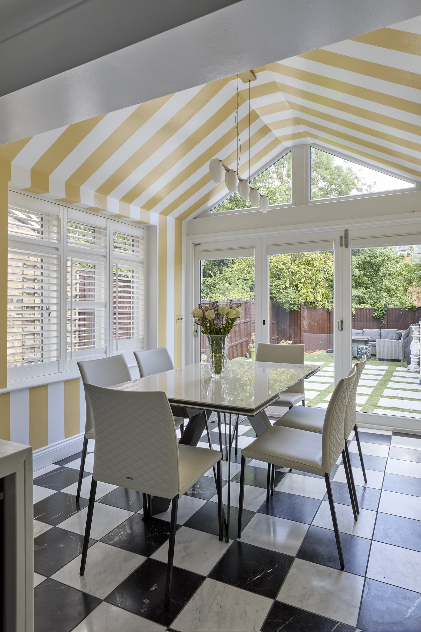 Dining area at Achilles Road within the glazed garden room, opening to the rear garden
