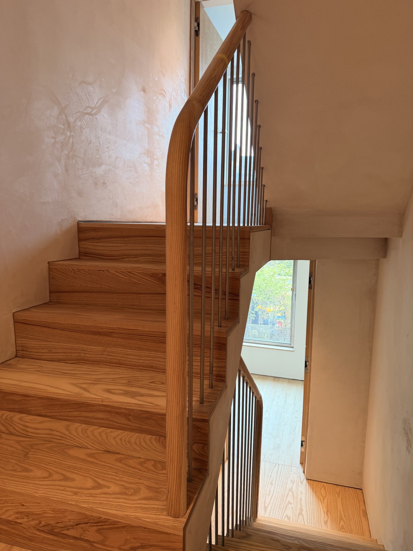 Caithness Road W14 — ash staircase with a continuous curved ash handrail on slender metal balusters