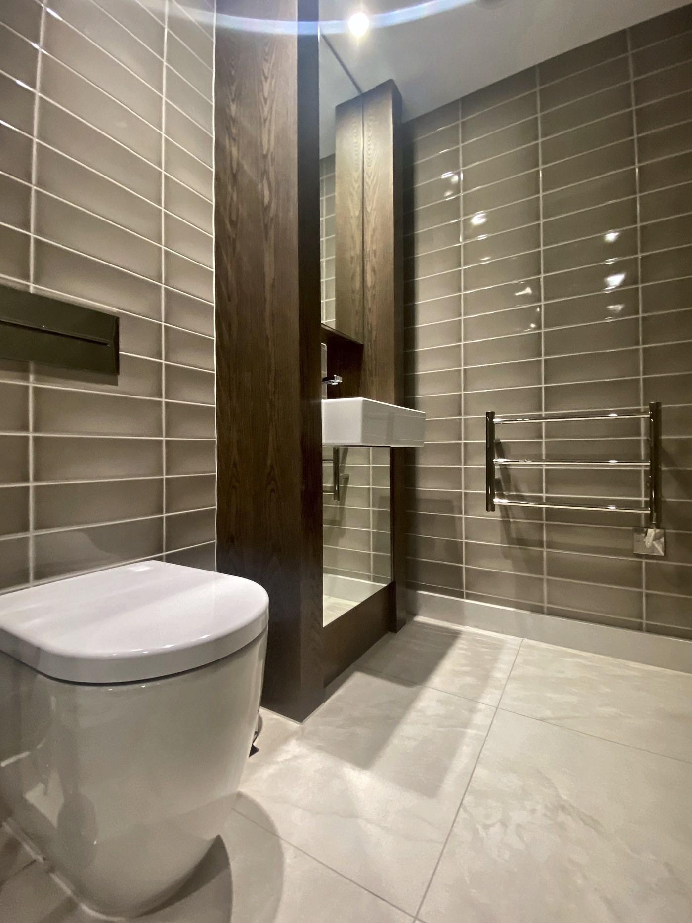 Shower room at Connaught Place lined in stone, with dark timber joinery and a wall-hung WC