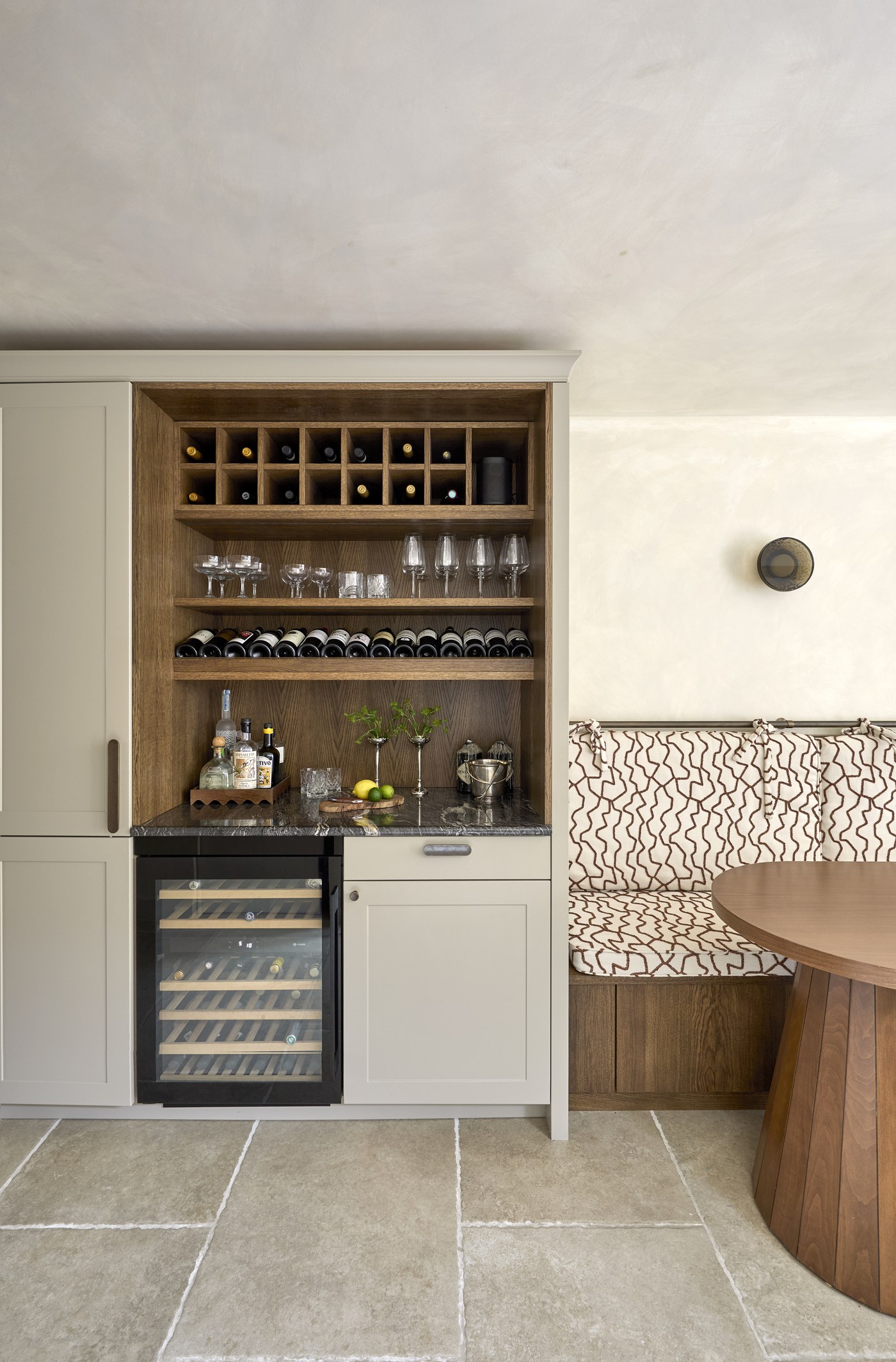 Honeywell Road SW11 — painted drinks cabinet with an oak-lined interior, wine rack, glass shelves and integrated wine fridge beside the dining banquette