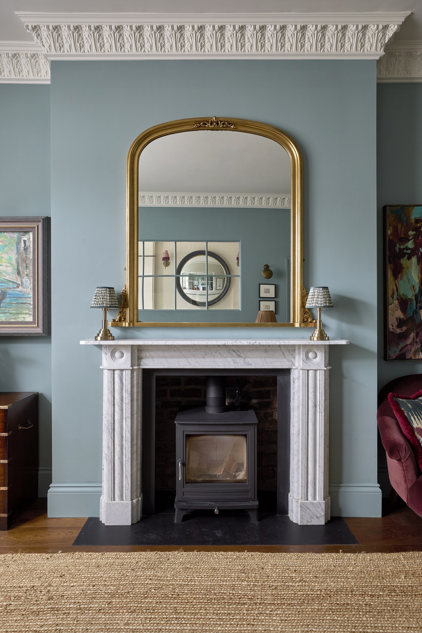 Marble chimneypiece with wood-burning stove and overmantel mirror at Melrose Gardens